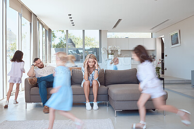Buy stock photo Exhausted mother and father looking stressed, while children run around playing in the lounge. Upset parents with headache siting on the couch, children playing around them. Young girls playing