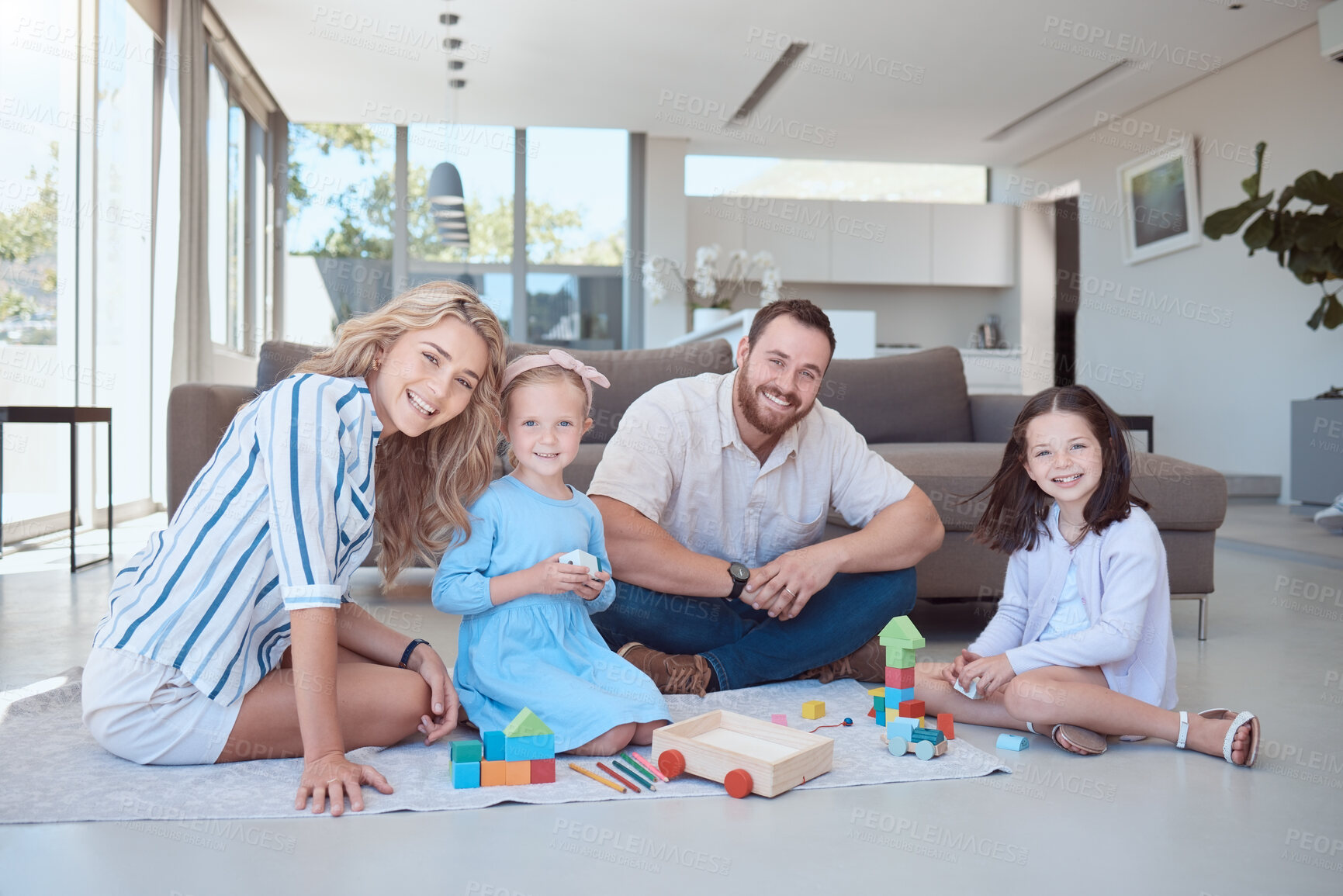 Buy stock photo Two little girls playing with colourful building blocks while sitting at home with parents. Couple playing with their two daughters at home. Portrait of happy caucasian family of four in their living room