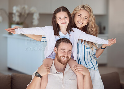 Happy caucasian family relaxing together at home. Carefree loving parents bonding with cute little daughter. Mom holding her adorable young playful girl while pretending to fly on her dad\'s shoulders