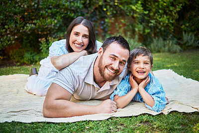 Buy stock photo Portrait of a happy caucasian family lying on a picnic blanket in the garden. Smiling family bonding, being affectionate outside while enjoying the day. Little boy relaxing with his parents