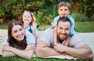 Buy stock photo Portrait of happy caucasian family lying outside on grass and having a picnic. Cheerful parents and their two children lying on top of them having fun outdoors at park or backyard on a sunny day