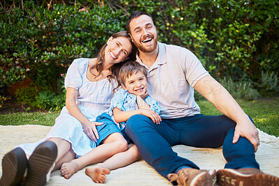 Buy stock photo Portrait of a happy caucasian family having a picnic in their garden, sitting on a blanket. Cheerful parents relaxing, enjoying a summer day with their little son. Young family relaxing outside