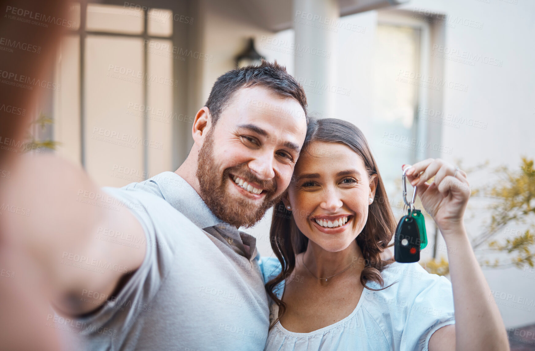 Buy stock photo Young caucasian couple taking a selfie holding house keys. Happy couple moving into their house. Smiling couple taking a photo outside before moving into their first real estate purchase