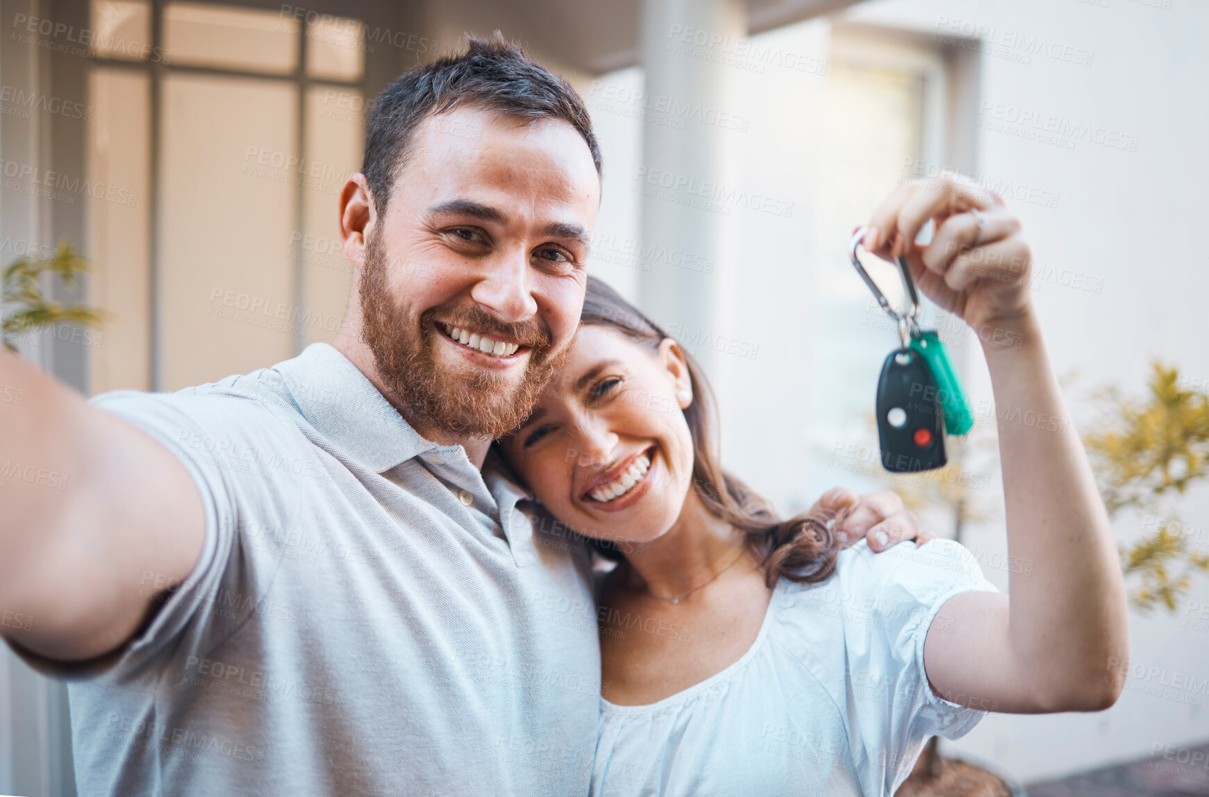 Buy stock photo Young happy caucasian couple taking a selfie and holding the keys to their new house together. Young man taking a photo while his girlfriend shows the keys to their new home. 