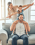 Happy young caucasian family bonding with their daughter in the living room at home on the weekend. Adorable little girl playing with her mother and father. Two parents showing love and affection