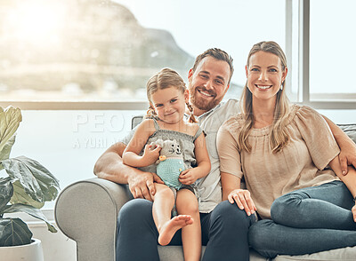 Buy stock photo Happy caucasian family smiling while relaxing and sitting on the couch together in the lounge at home. Two loving parents spending time with their little daughter 