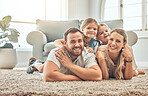 Young family in the living room at home. Portrait of an affectionate and happy family lying on the floor of the lounge. Spending quality time together. A mother, father and two sisters at home