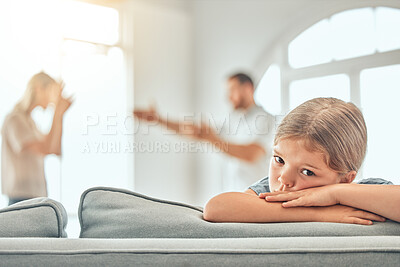 Little unhappy young caucasian girl sitting on sofa while parents arguing in the lounge at home