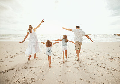 Buy stock photo Happy caucasian family walking together on the beach. Playful family with two little girls walking with their arms outstretched on the beach while on vacation 
