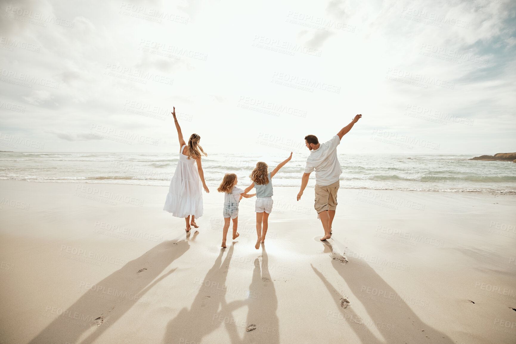 Buy stock photo Back of happy caucasian parents with daughters enjoying free time on a beach. Little girls bonding with their mother and father and playing on weekend. Family pretending to fly with arms outstretched