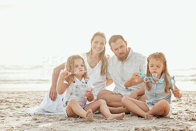 Buy stock photo Happy caucasian family go four enjoying a vacation at at the beach. Young smiling couple playing in the sand with their two adorable daughters. Two cute sisters enjoying a summer day with mom and dad