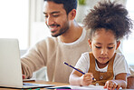 Young mixed race father working from home on a laptop with his little daughter drawing. Child drawing next to dad who is using a computer. Girl with a curly afro doing homework while her dad works