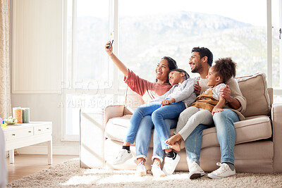 Family selfie of an african american woman, her husband and daughters sitting on the sofa in the living room at home. A young wife taking photos with her happy mixed race family in the lounge