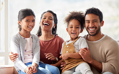 Buy stock photo Portrait of smiling mixed race family laughing and relaxing on sofa at home. Carefree loving hispanic parents bonding with cute little daughters. Happy kids spending quality time with mom and dad