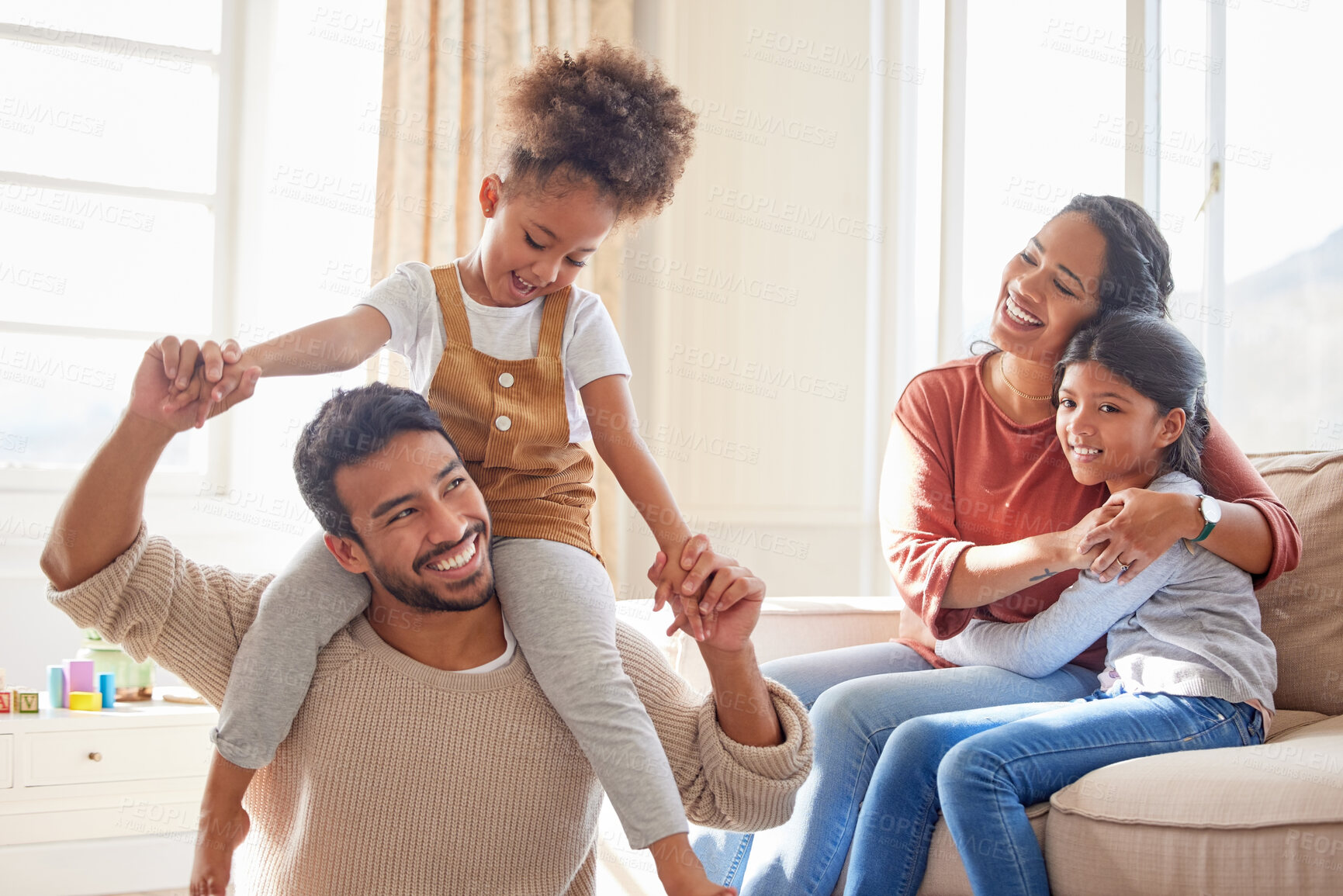 Buy stock photo Dad, mom and children in home, shoulders and happiness with playing games, hug or bonding in lounge. Father, mother and daughter with care, love and together with embrace, quality time or living room
