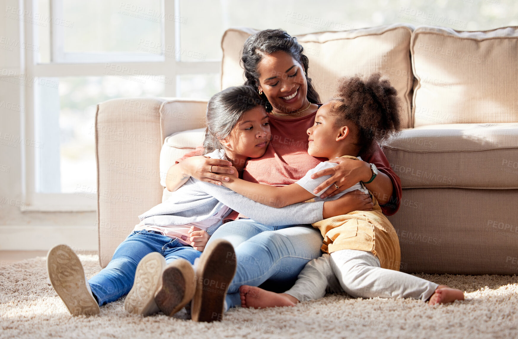 Buy stock photo Mixed race mother hugging her daughters in the living room at home. Indian woman showing love and affection to her girls. Hispanic siblings embracing their single parent during free time on a weekend