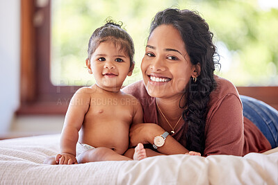 Buy stock photo Portrait of young mixed race mother lying with her adorable baby girl on the bed in a bedroom at home. Hispanic woman spending time with her cute little daughter on a bed at home