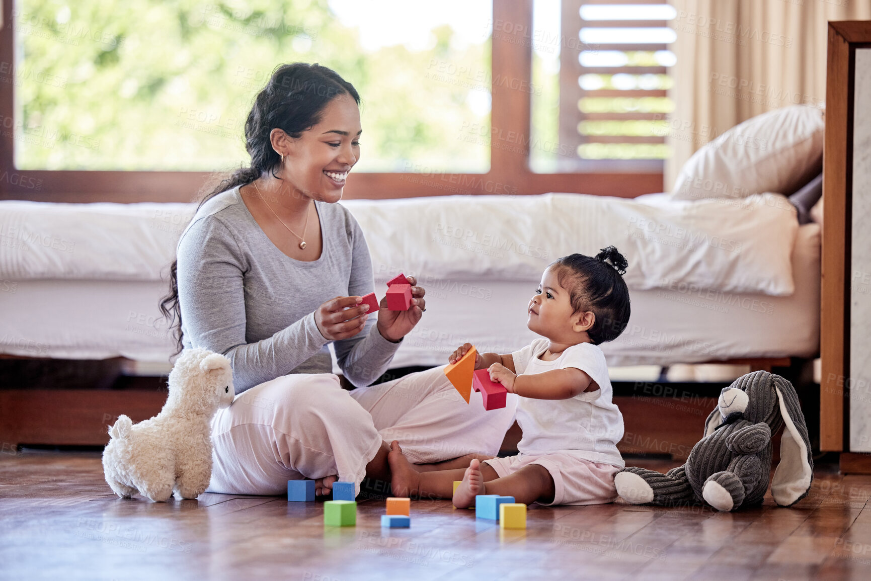 Buy stock photo Beautiful young woman and single mother playing toy blocks with her adorable little baby daughter in the bedroom at home. Happy mixed race woman bonding with her little girl. Education starts at home