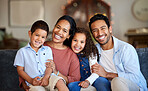 Portrait of smiling mixed race family relaxing together on sofa at home. Carefree loving hispanic parents bonding with cute little son and daughter. Happy kids spending quality time with mom and dad