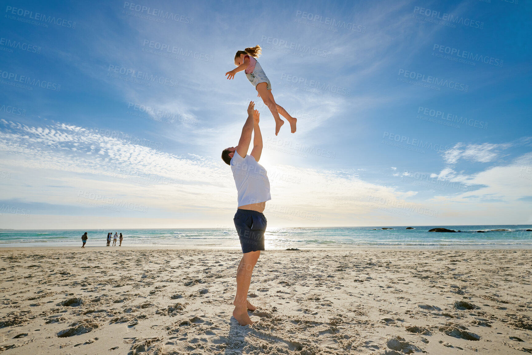 Buy stock photo Father lifting daughter, having fun on the beach. A smiling young man playing with his cute little girl on vacation. Fun family vacation