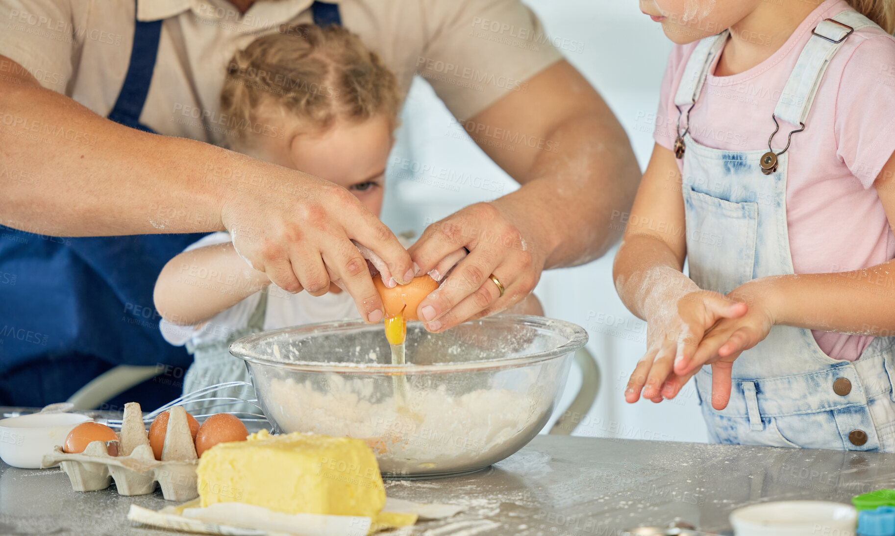 Buy stock photo Father cracking egg into a bowl. Parent baking with his children. Family baking in the kitchen. Caucasian family baking together. Father bonding with his daughters and cooking. Kids baking together