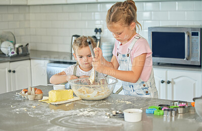 Buy stock photo Two messy little girls baking in the kitchen at home. Caucasian focused sisters learning to make a dessert and cook. Adorable children bonding and helping each other to prepare a recipe for the house