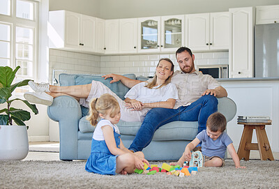 Buy stock photo Happy caucasian parents sitting on the couch watching their little son and daughter play with their toys in the lounge at home. Brother and sister playing with their toys together