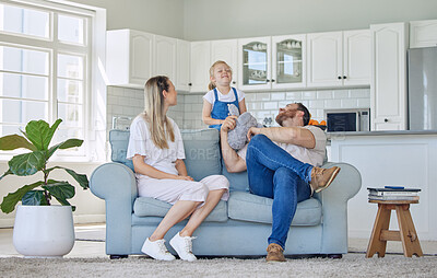 Buy stock photo Caucasian parents with a daughter enjoying free time in a living room at home. Smiling cute little girl bonding with her mother and father and playing on a weekend. Playful family laughing on a sofa