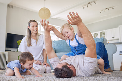Family with daughter and baby son playing on the carpet in living room. Dad playing with his little girl and baby while mother sits by and watch them. Happy caucasian family bonding at home