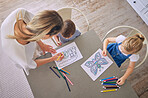 Above shot of little girl and boy sitting at table with colourful pencils and pictures while colouring with mom helping. Caucasian mother with two kids enjoying educational pastime and being creative
