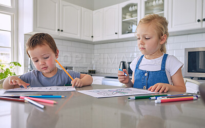 Buy stock photo Young little caucasian siblings drawing with colored pencils while sitting at the kitchen counter at home. Brother and sister being creative colouring in pictures at home
