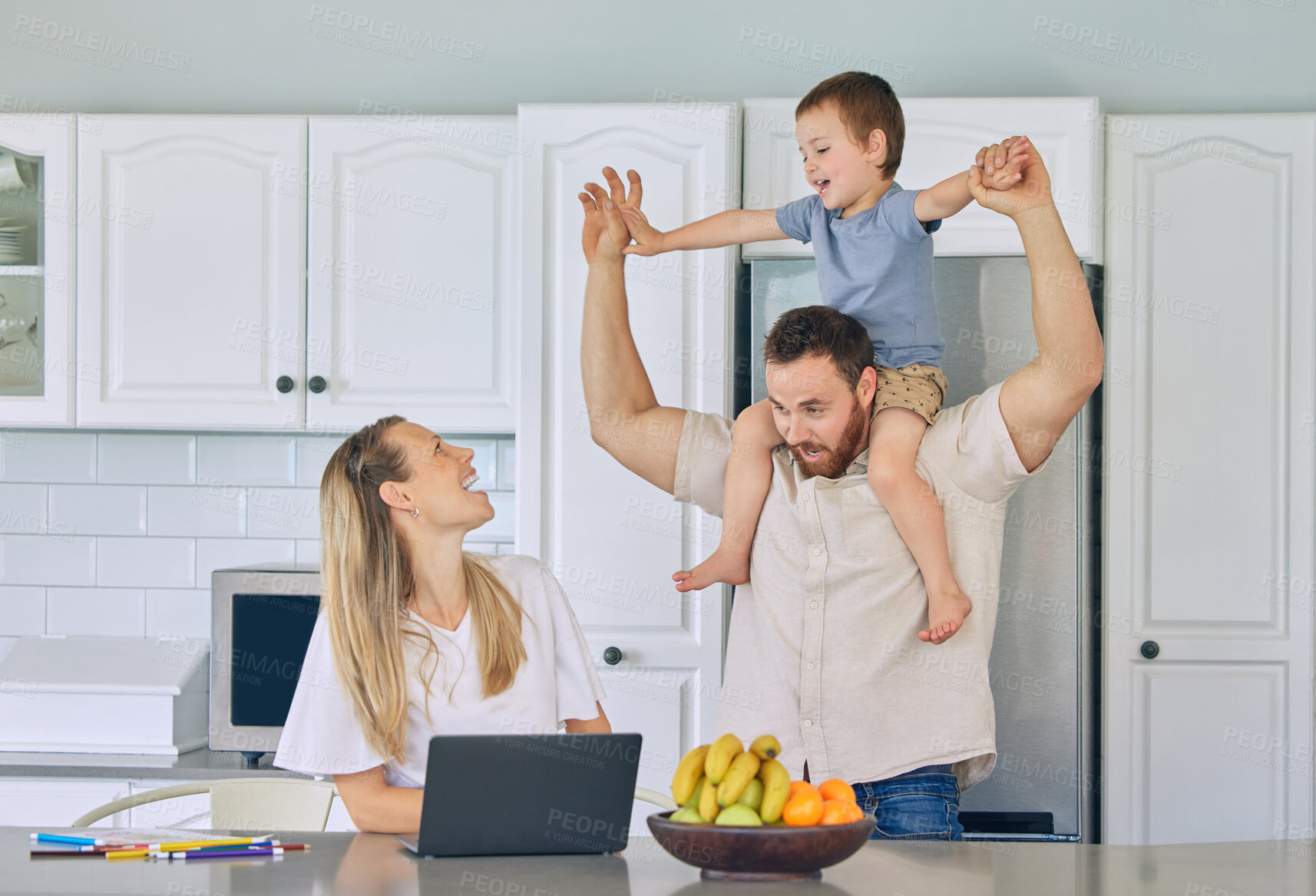 Buy stock photo Happy young caucasian family having lunch time with fresh fruit in a bright kitchen. Beautiful young mother and father playing with their cute son while using a laptop at home against light copyspace 