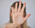 Closeup of of the hand of a caucasian business woman gesturing stop while standing against a grey background. Stop gender based violence, sexual harassment and bullying. Take a stand. Enough is enough