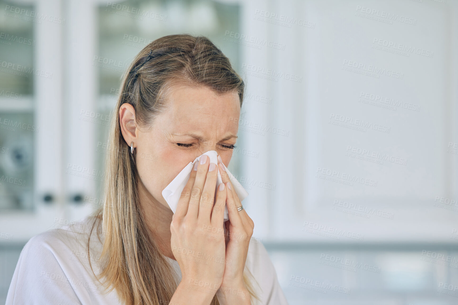 Buy stock photo Sick, tissue and woman blowing her nose in the kitchen for a cold, flu or sneeze at her home. Illness, virus and young female person sneezing with allergies, hay fever or covid in her apartment.