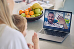 Mother and son talking to husband through video call on a laptop at home. Long distance caucasian father waving to his son during a video conference call. Young family communicating through technology