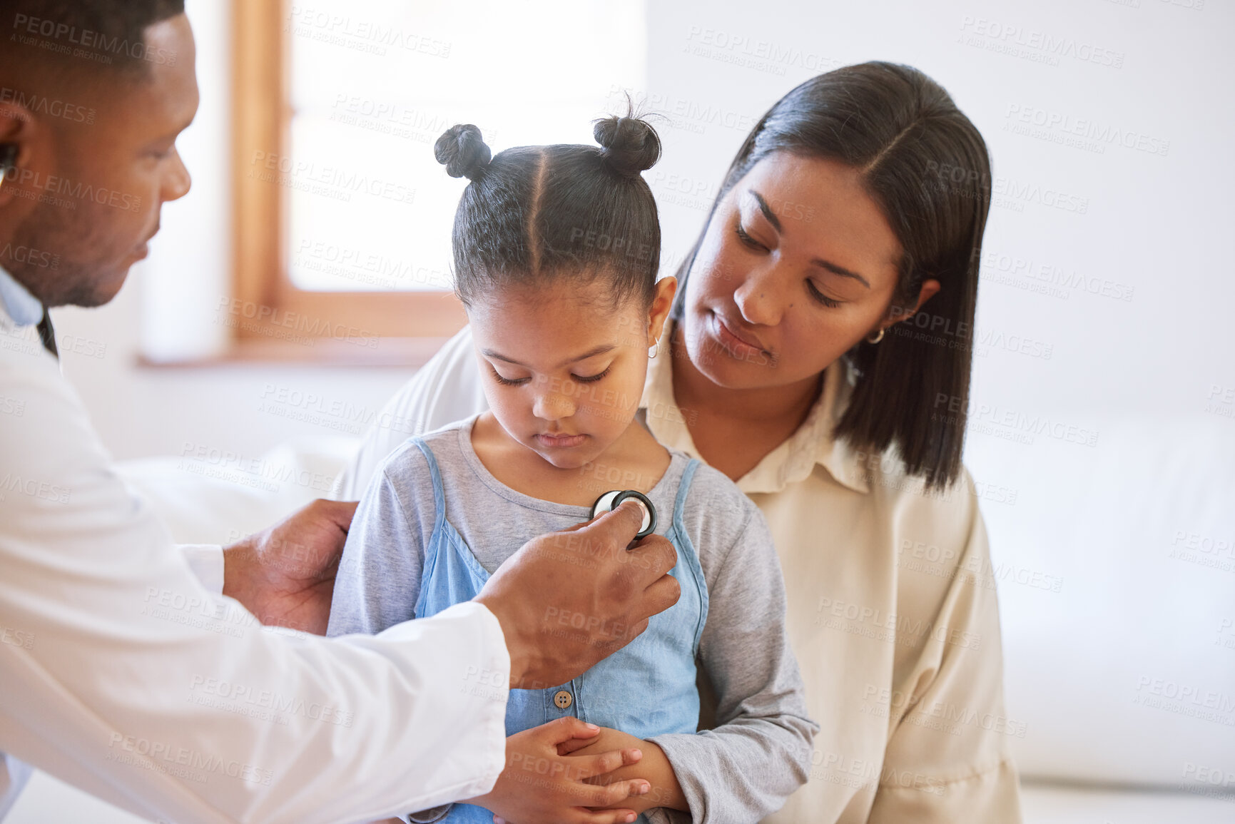 Buy stock photo Sick child at doctor's office with her mother. Little girl sitting with mother while male paediatrician listen to chest heartbeat. Male doctor examining child with stethoscope. Mom holding kid during doctor visit