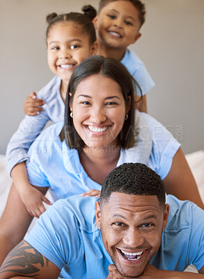 Buy stock photo Portrait of a smiling boy and girl lying on their parents in a pile at home. Mixed race couple bonding with their son and daughter. Hispanic siblings enjoying free time with their mother and father