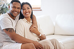Portrait of happy mixed race couple sitting together at home. Loving and affectionate man sitting with his arm around his wife relaxing on the couch at home