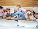 Relaxed african american family smiling while lying on the couch. Above shot of a young happy black couple relaxing while talking to their two young adorable kids on a sofa at home