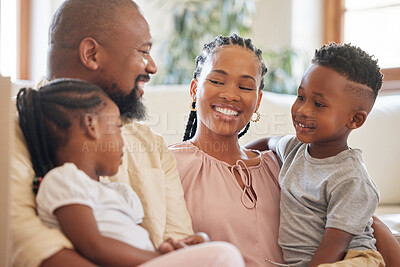 Buy stock photo Relaxed african american family smiling while sitting on the couch. Shot of a young happy black couple relaxing on the sofa while talking to their two young adorable kids at home 