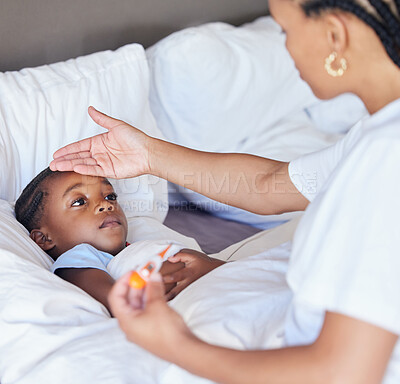 Sick little girl in bed while her mother uses a thermometer to check her temperature. Black single parent feeling daughter\'s forehead. African American child feeling ill while her mother checks fever