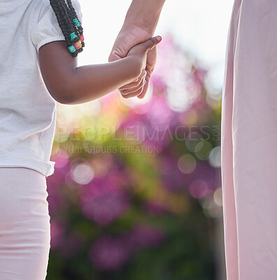 Closeup mother and daughter holding hands while walking outside in the garden. A great role model and mentor for her girl child. A daughter will always look up to and follow in their mom\'s footsteps