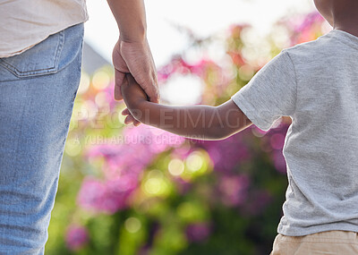 Closeup father and son holding hands while walking outside in the garden. A great role model and mentor for his boy child. A son will always look up to and follow in their dad\'s footsteps