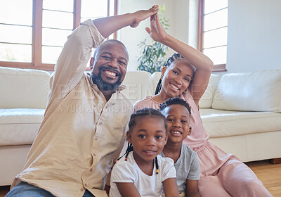 A young african american couple sitting with their children at home and making a house gesture over their children at home