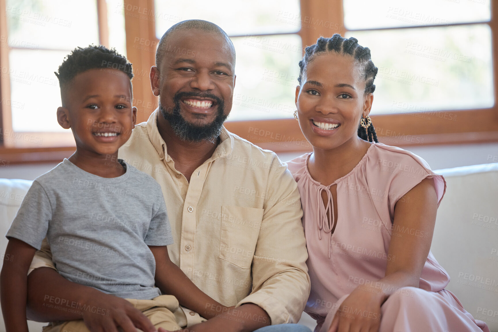 Buy stock photo Portrait of a young african american family sitting on the sofa together and smiling at home