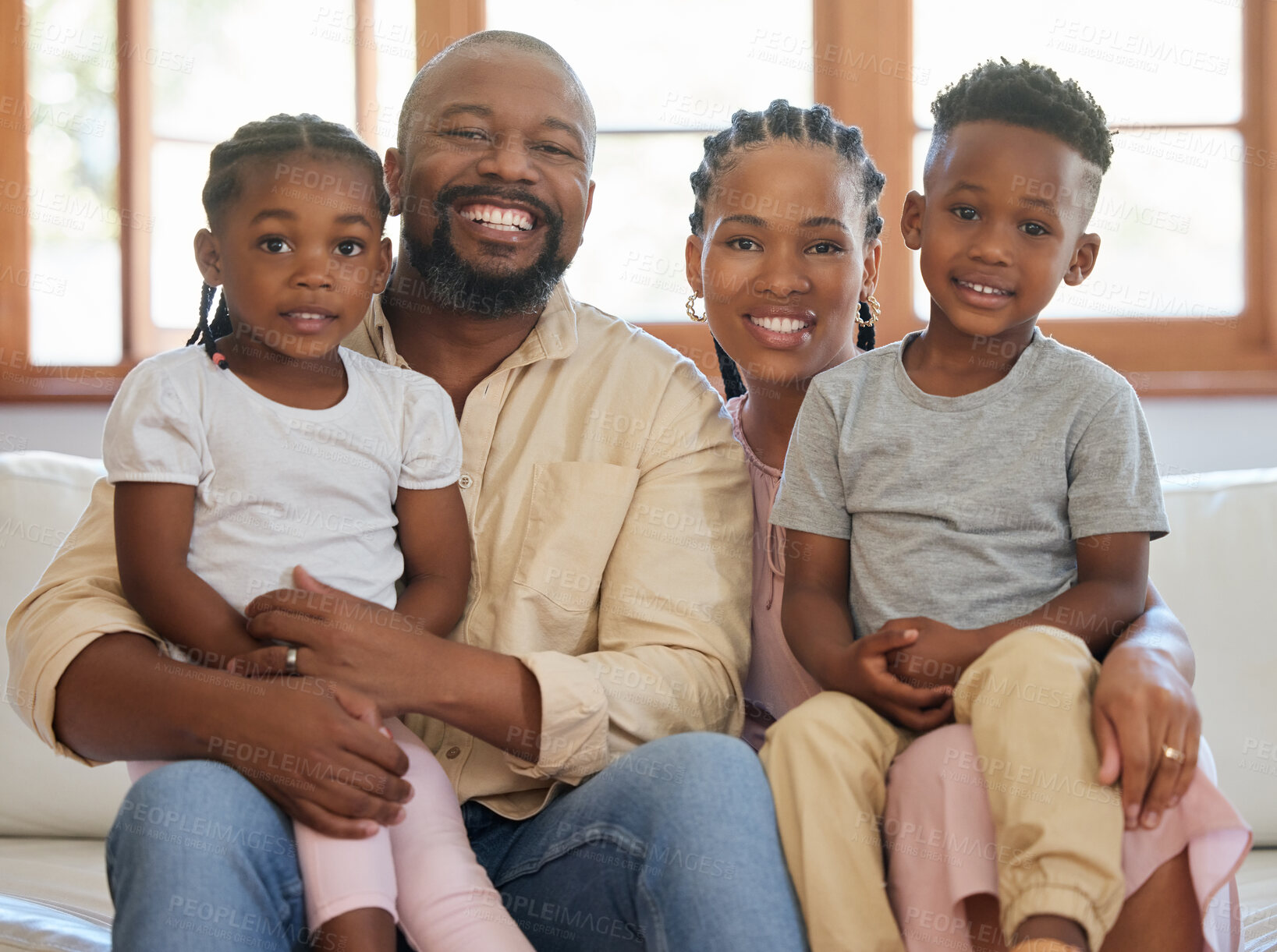 Buy stock photo Portrait of a young african american family sitting on the sofa together and smiling at home