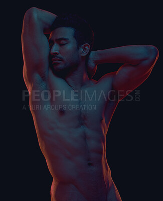Seductive naked man posing in a studio. Muscular model flexing his biceps. Strong, nude man posing on a dark background. Alluring man posing in a studio. Nude male model on a dark background