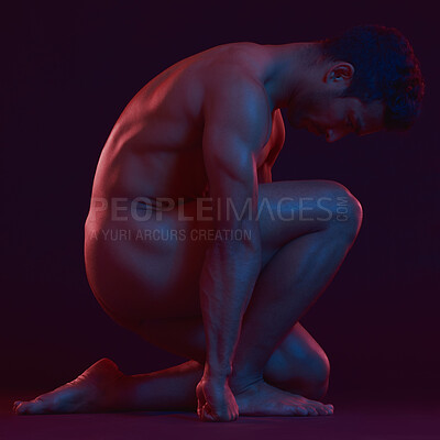 Athletic handsome mixed race man athlete posing on his knee with naked body in red blue gradient neon light on black studio background