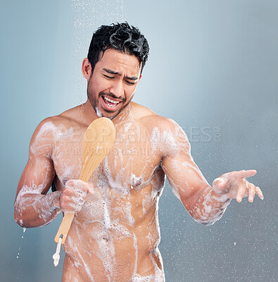 Buy stock photo Handsome young man singing in the shower. Happy mixed race male holding shower brush while rinsing soap off his body under clean running water. Handsome hunk doing his morning self-hygiene and body care routine