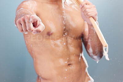 Buy stock photo Mixed race man singing in a shower and pointing. Unknown hispanic athlete enjoying a morning shower and using a back brush as a microphone while dancing. Fit man isolated against a blue background